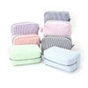 A collection of five striped cosmetic bags in shades of pink, purple, and green stacked on a white background.