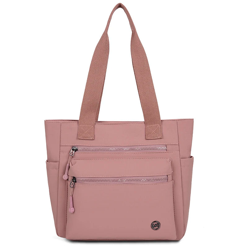 A pink canvas tote bag with padded straps and zippered pockets.