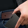 A hand is inserting a black patterned slim RFID blocking wallet into the pocket of dark blue fabric.