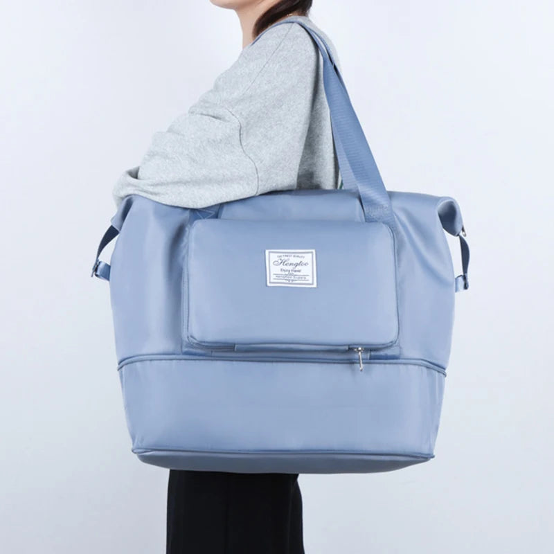 A light blue expandable travel organizer bag with a zippered pocket and shoulder straps.