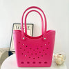 حقيبة كتف من مادة إيڤا مقاومة للماء باللون الوردي الفاتح ومصممة بثقوب، معروضة على سطح أبيض.