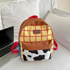 A brown and yellow plaid backpack with a cow print front is resting on a white surface next to a laptop.