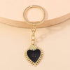 Gold-toned heart keychain featuring a black heart pendant with sun eye detailing.