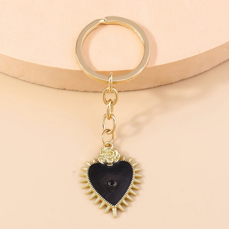 Gold-toned heart keychain featuring a black heart pendant with sun eye detailing.