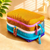 A yellow and orange multi-compartment travel toiletry organizer bag lying on a light surface.