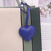A purple heart-shaped leather keychain charm attached to a green and cream striped bag.