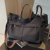 A dark gray lightweight nylon tote bag with brown leather handles and multiple internal pockets.