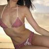 A woman wearing a red plaid bikini set with a halter top and low-rise waist, posing outdoors.
