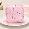 A pink fabric pouch designed for storing sanitary napkins with a white floral pattern, resting on a white plate.