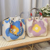 A light beige knitted bucket handbag with purple and yellow floral embroidery and red and white braided handles.
