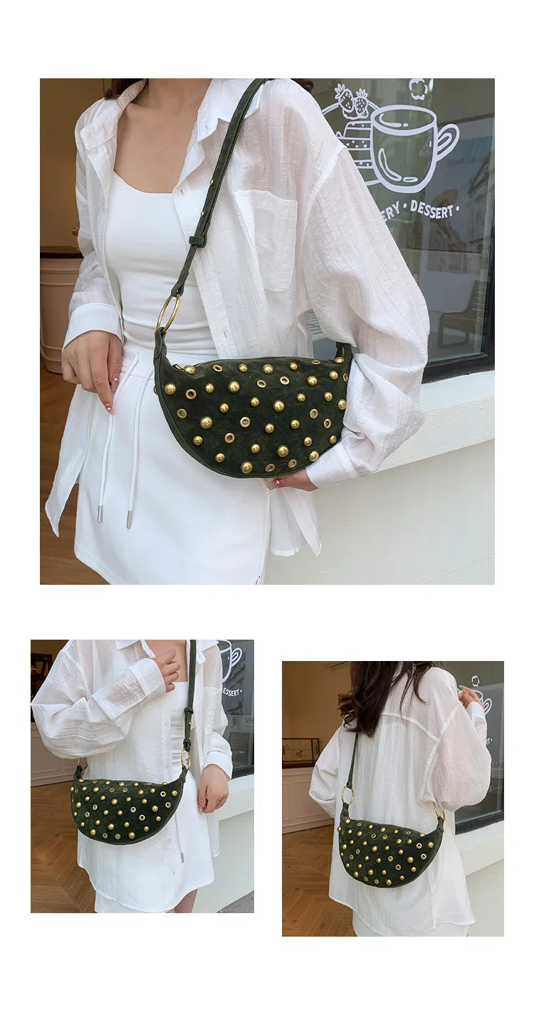 A woman holds a dark olive green faux suede hobo crossbody bag with gold rivet accents against a white shirt.