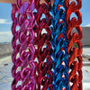 A close-up of a chunky gold acrylic Cuban link necklace featuring vibrant pink, blue, and red colored links.