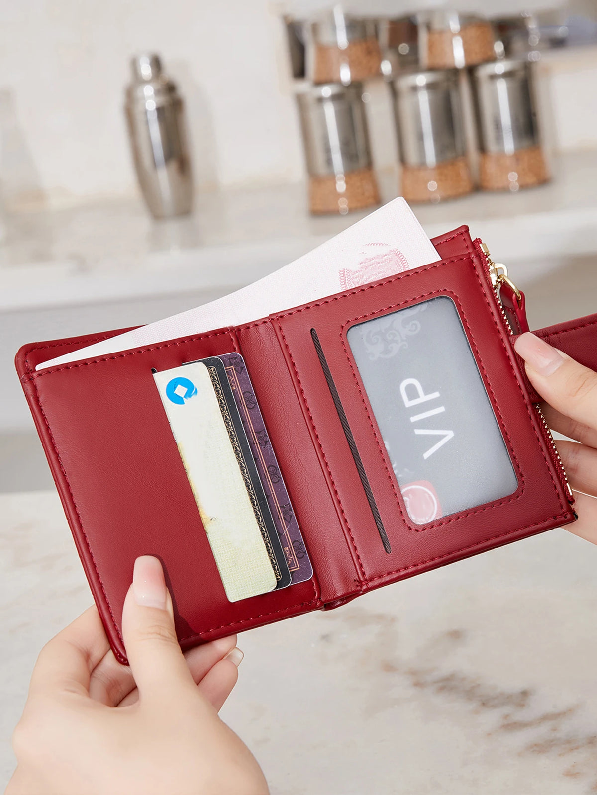 A close-up of a red PU leather bifold wallet with a zipper closure showing an ID card and credit cards.