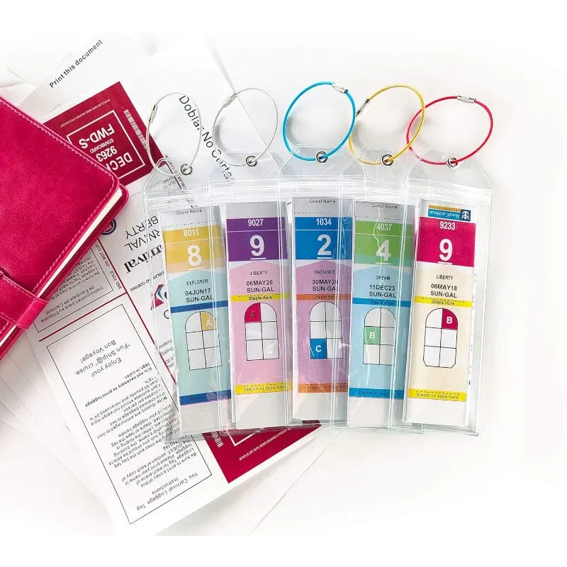 Un juego de soportes para etiquetas de equipaje transparentes con correas rosas y doradas y etiquetas de varios tamaños.
