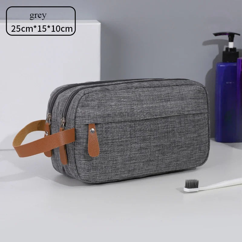 A grey portable travel storage pouch with a brown leather strap is shown on a white surface.