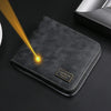 A black leather zipper wallet with a gold engraved nameplate is shown under a bright light.
