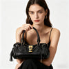 A woman models a black vegan leather tote bag with a gold lock buckle clip.
