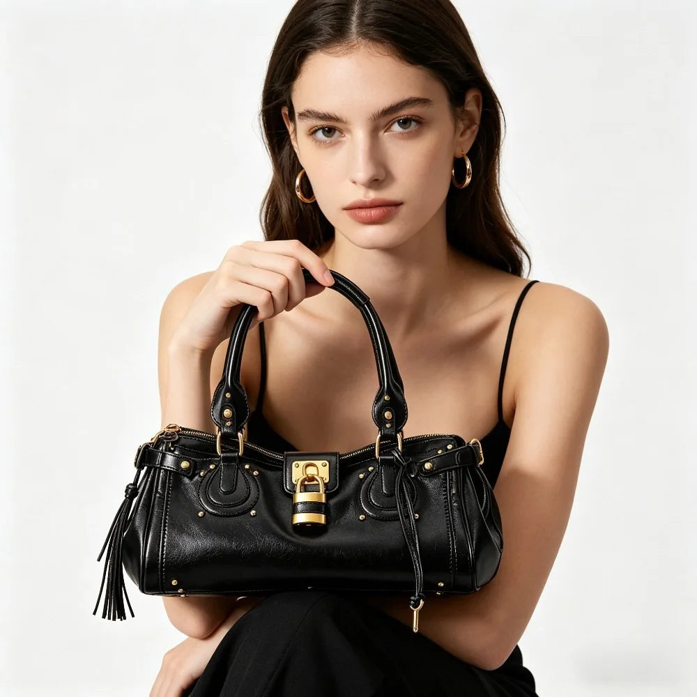 A woman models a black vegan leather tote bag with a gold lock buckle clip.