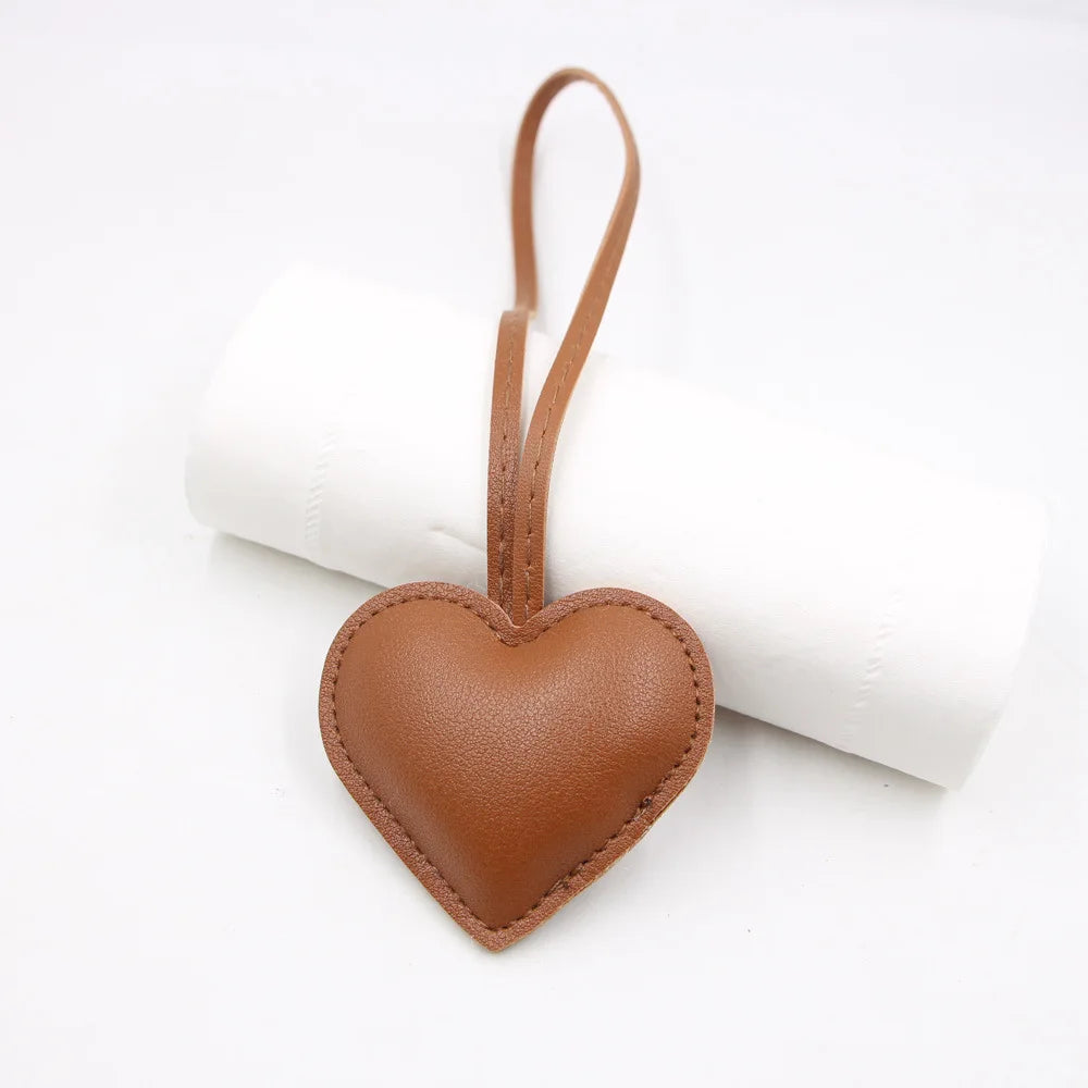 A brown PU leather heart-shaped keychain attached to a white rolled paper.