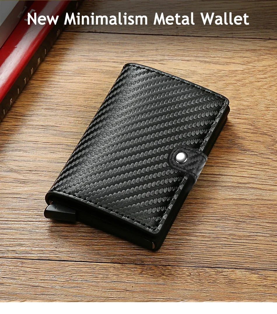 Portefeuille minimaliste en métal noir avec une couverture en cuir texturé, posé sur une surface en bois.