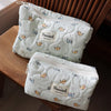 A white quilted cosmetic storage pouch with a light blue pattern of small cats resting on a wooden surface.