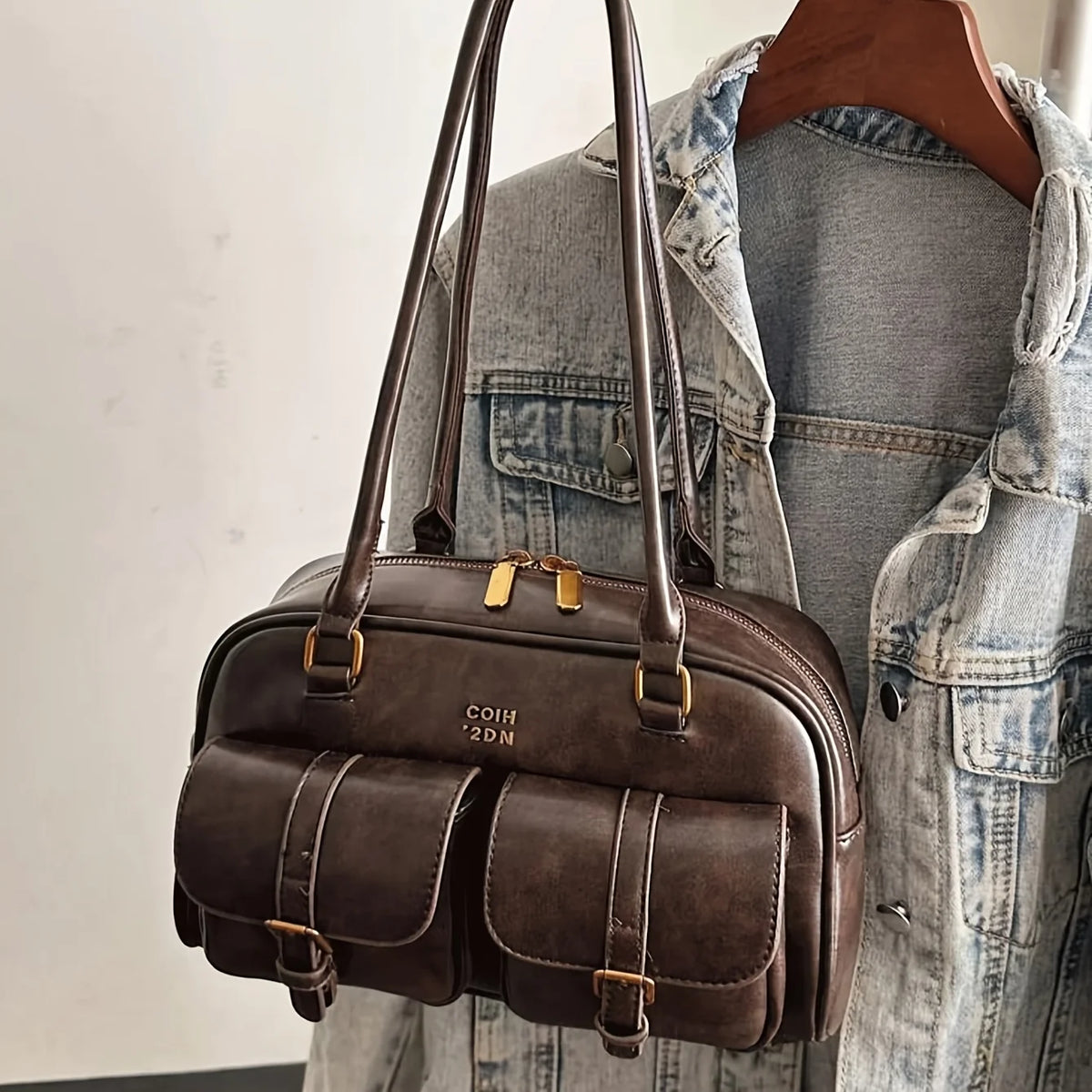 A brown leather vintage letter print crossbody bag is displayed against a denim jacket.