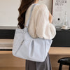 A woman holds a light blue polka dot shoulder tote bag in a soft, natural light setting.