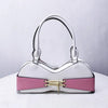 A white shoulder bag with a playful bra silhouette featuring pink accents and a bow detail.