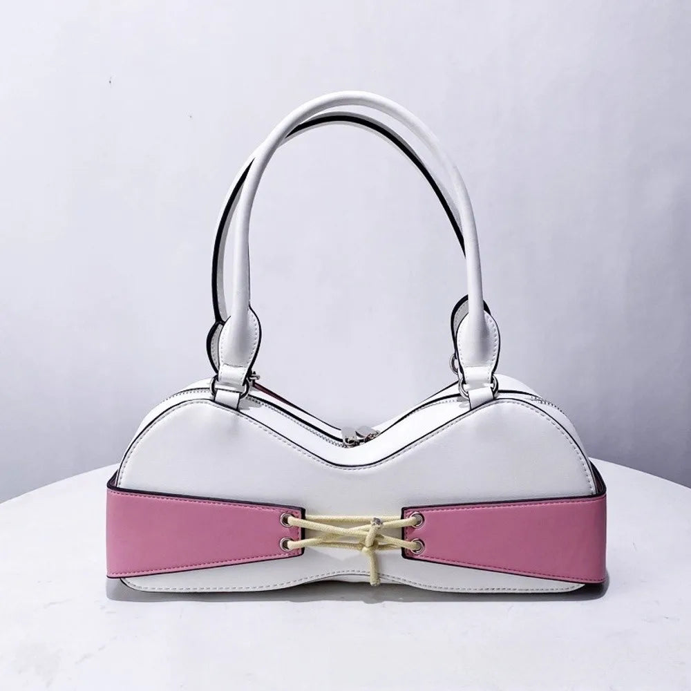 A white shoulder bag with a playful bra silhouette featuring pink accents and a bow detail.