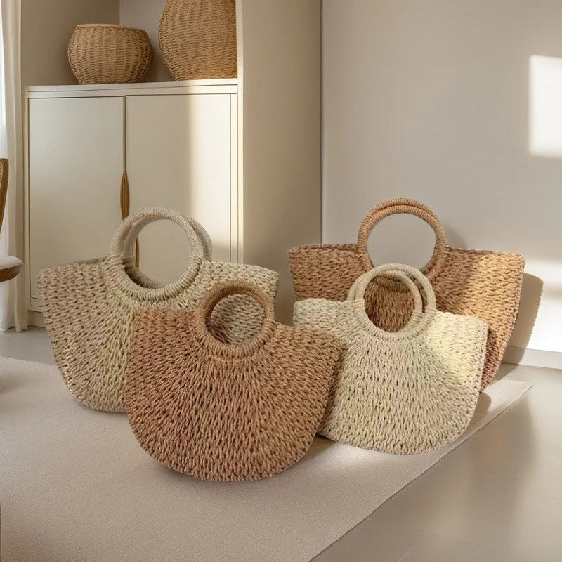 A collection of natural beige and tan handwoven rattan beach bags displayed on a light floor.