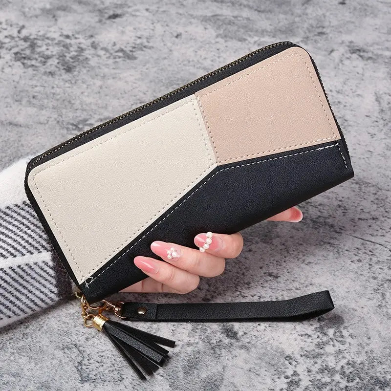 A beige and black checkered fashion zipper wallet is held by a hand on a gray surface.