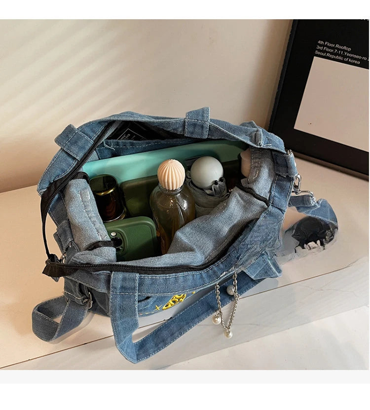 A blue denim crossbody bag is open, showing its interior lined with green and clear glass containers.