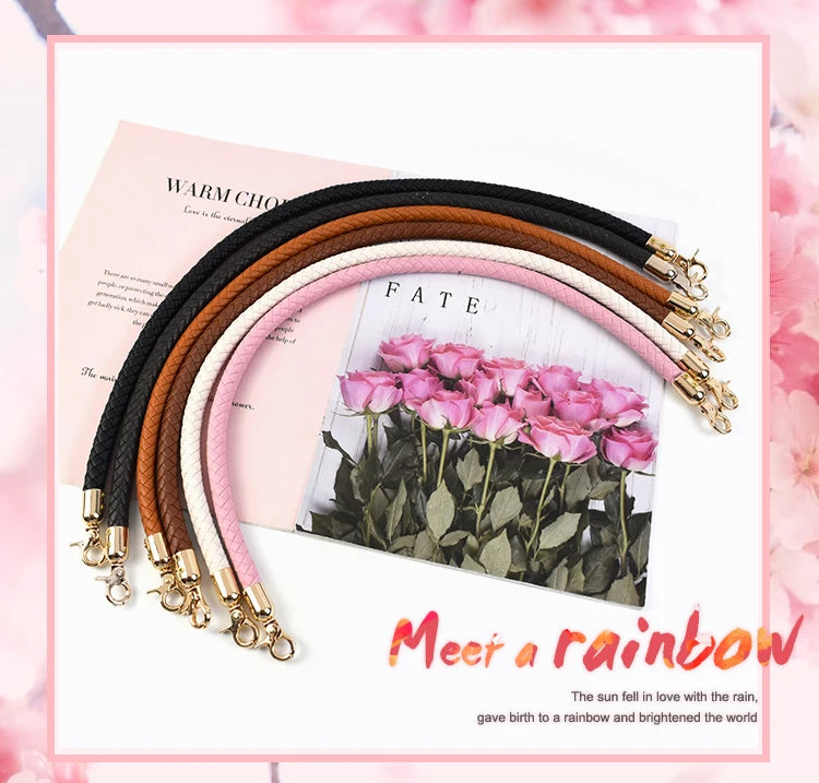 A collection of rainbow colored leather bag handles with metal buckles displayed on a pink background.