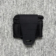 Black tactical mesh drawstring utility pouch bag resting on a textured gray surface.