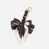 A black and white patterned bow bag chain strap extension with a gold-toned clasp.