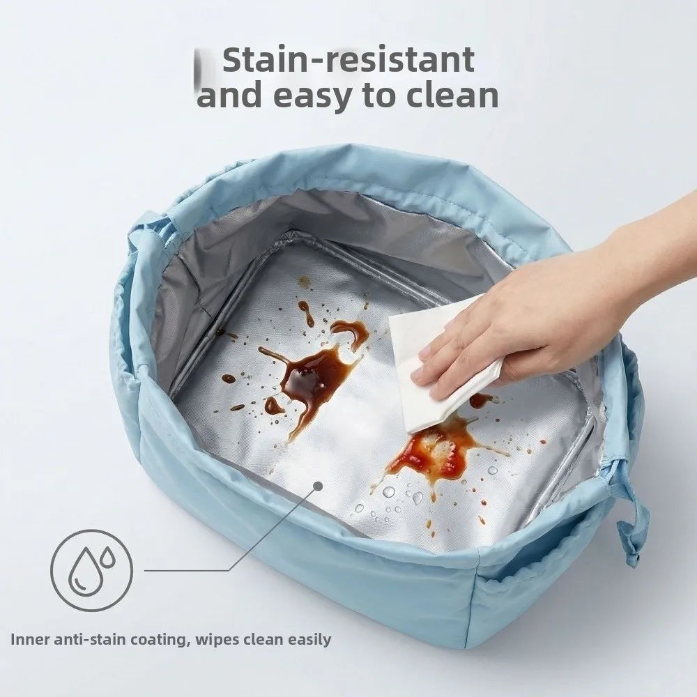 A hand is cleaning a stainless steel insert inside a light blue insulated lunch bag, demonstrating its stain-resistant coatin