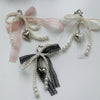 A pearl bowknot keychain featuring pink and white lace ribbons with heart charms.