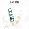 A close-up photo of a gold-colored hardware shoulder strap product with green and white patterned fabric.