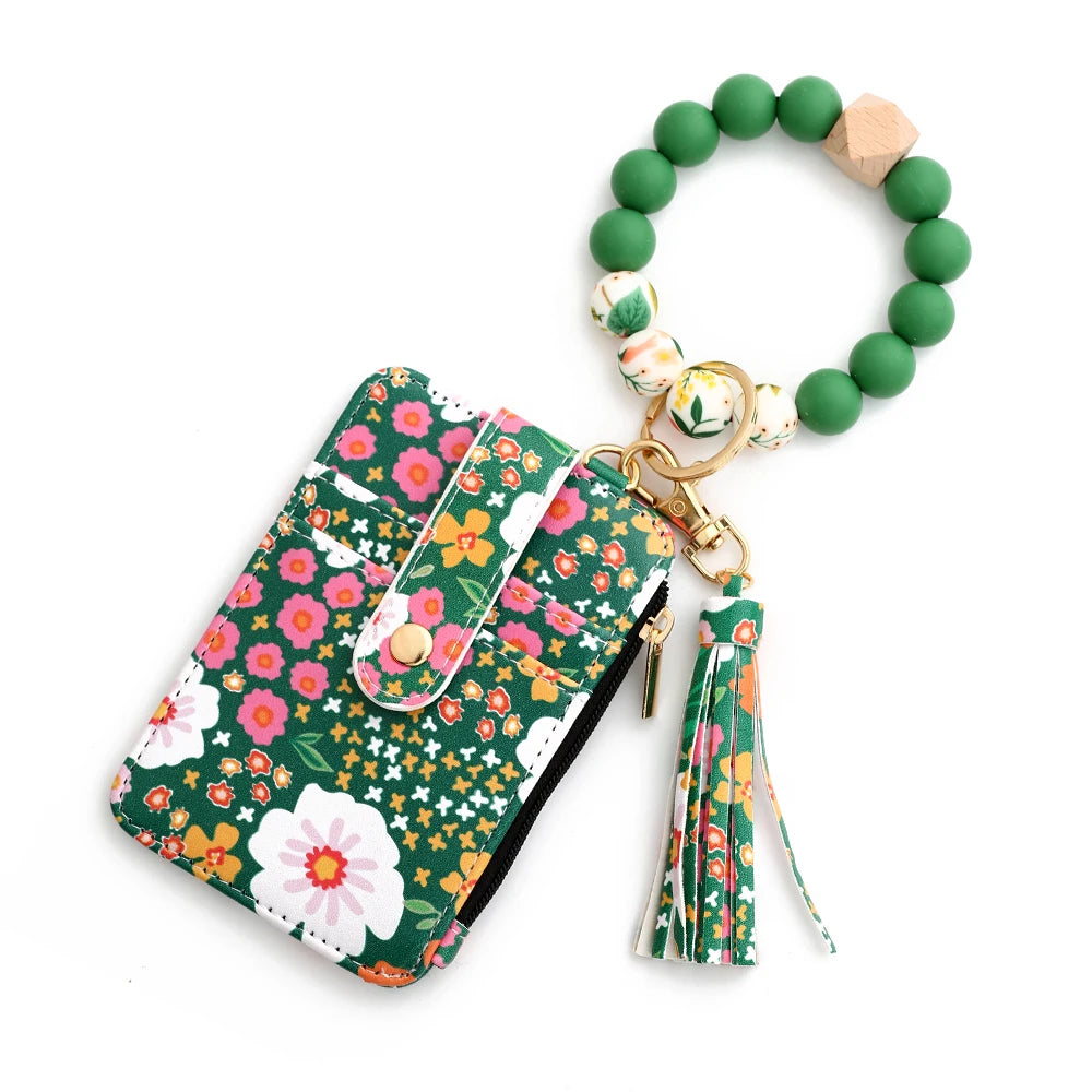 A green silicone bead necklace with a wooden charm and a PU leather key chain wallet featuring floral embroidery.