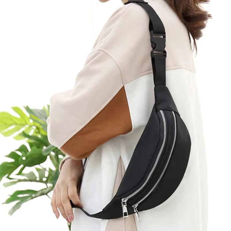 A black nylon crossbody sling bag is worn on a person's shoulder, featuring a zipper closure.