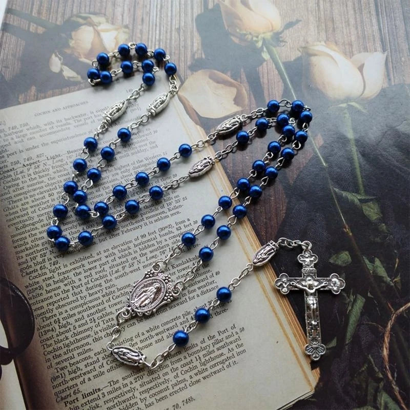 Blaue Rosenkranzkette mit silbernem Kreuzanhänger auf einem Textblatt.