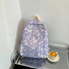 A purple backpack with a white butterfly pattern resting on a metal shelf next to a cup of tea.