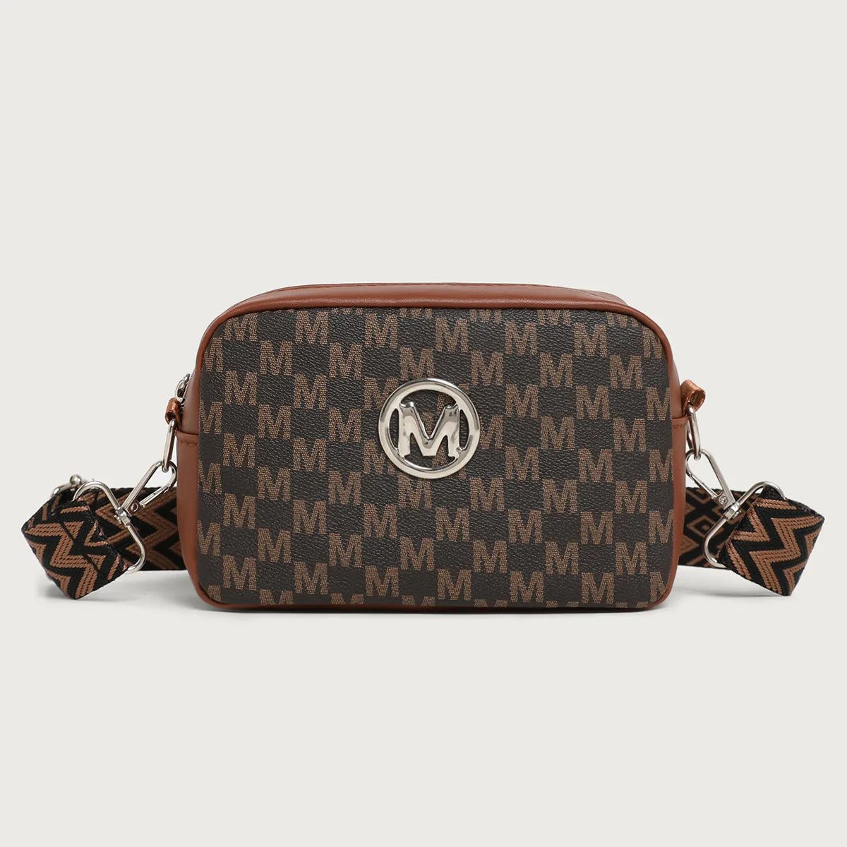 A brown leather crossbody bag featuring a monogram pattern and a silver M logo.
