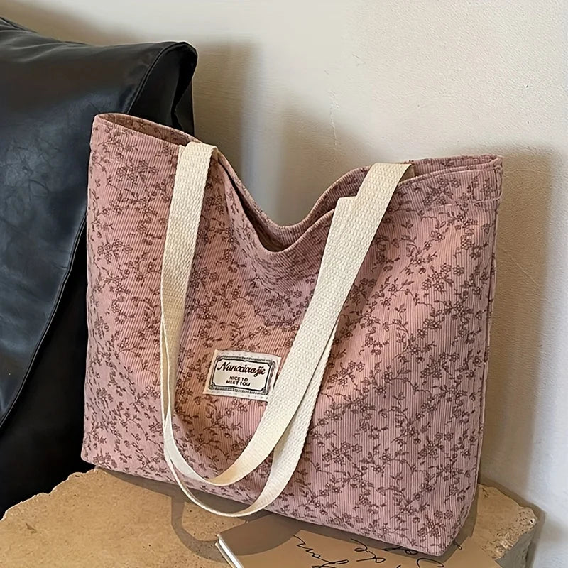 A pink bohemian corduroy tote bag with a floral pattern is displayed against a white background.
