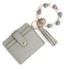 A light gray silicone bead and leather card wallet with a beaded bracelet attached.