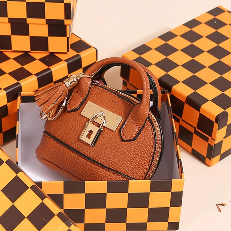 Portefeuille-clés en PVC marron de luxe présenté dans une boîte cadeau à carreaux noir et orange.