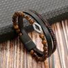 A stack of men's multi-layer leather bracelets featuring tiger eye beads on a dark background.