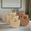 A collection of natural beige and tan handwoven rattan beach bags displayed on a light rug.