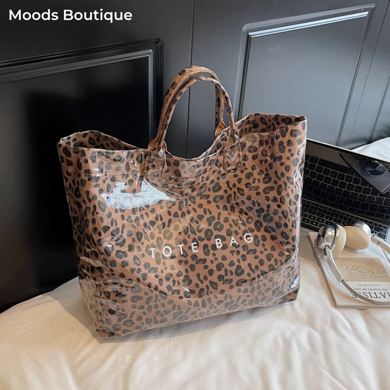 Braune Leopardenmuster-PVC-Tasche auf weißem Stoff neben einem Laptop