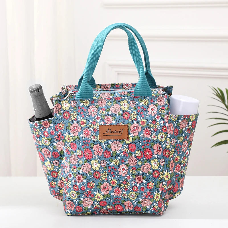 Bolsa térmica estampada en color verde azulado con asas sobre una superficie blanca.